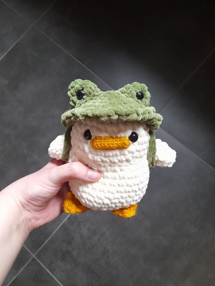 a hand holding a crocheted stuffed animal with a hat on it's head