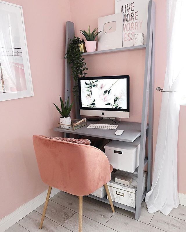 a desk with a computer on top of it and a pink chair in front of it