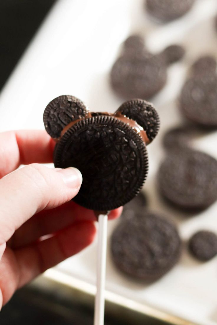 a hand holding a oreo cookie on a stick