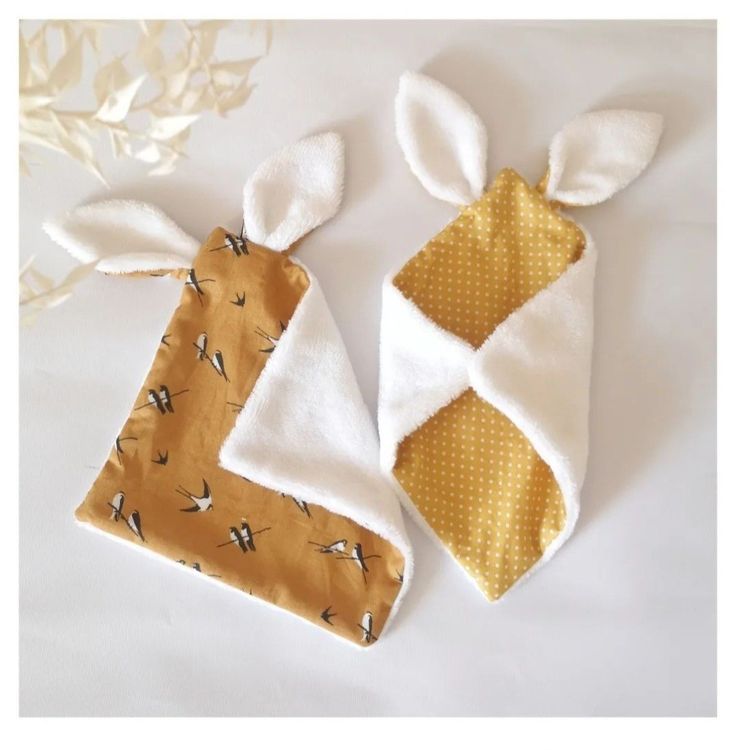 two bunny ears are on top of the baby's bib and one is yellow with white polka dots