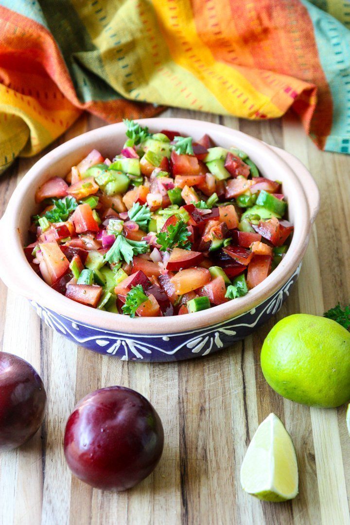 a bowl filled with fruit sitting on top of a wooden table next to two limes