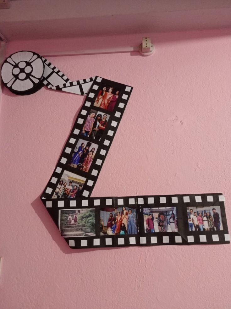 a black and white film strip with pictures on it hanging from the side of a pink wall