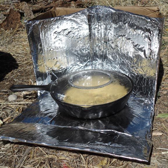 an iron skillet sitting on top of a piece of tin foil in the grass