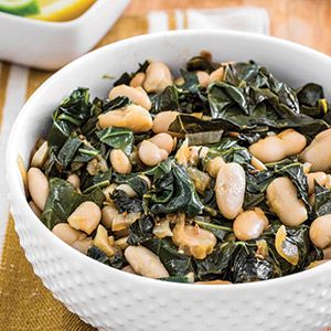 a white bowl filled with spinach and chickpeas on top of a table