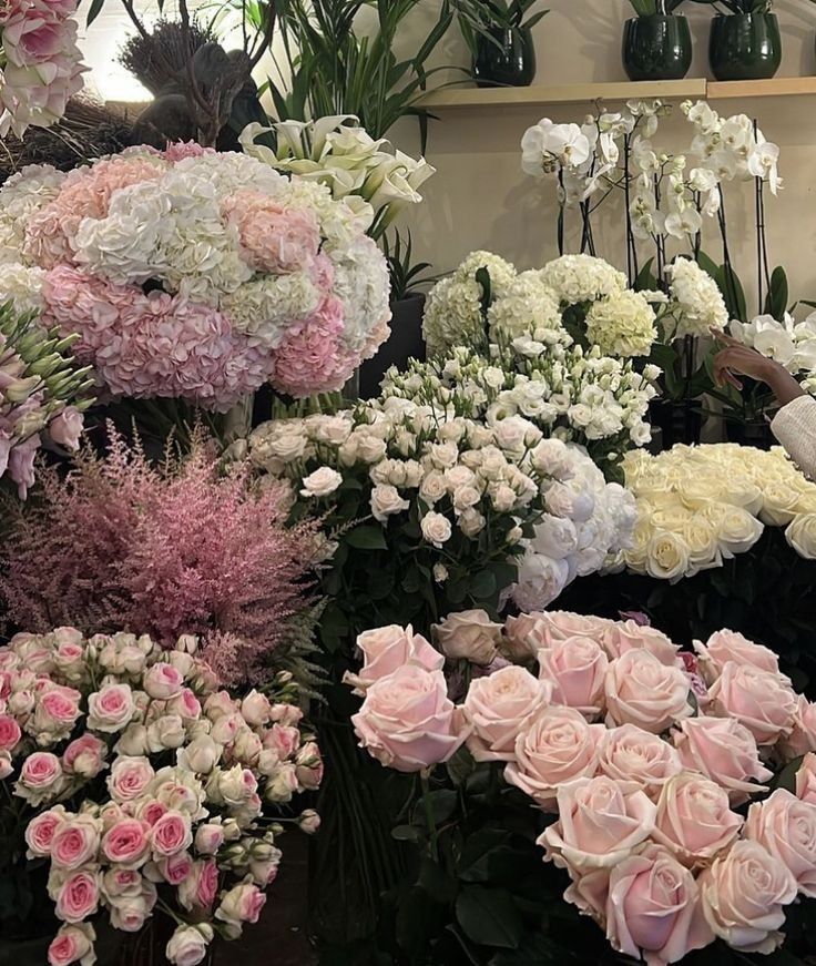 a bunch of flowers that are sitting on the ground in front of some shelves with vases