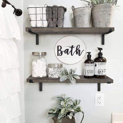 a bathroom with two shelves above the toilet and some plants on the shelf below it