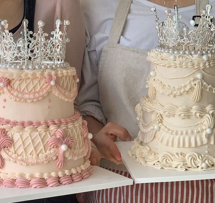 three tiered cakes with tiaras on top are being held by two women in aprons