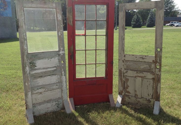 two old doors sitting in the grass next to each other on either side of an open door