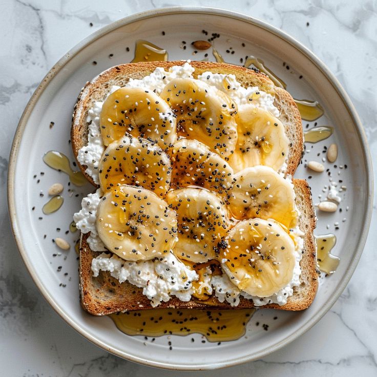 an open face sandwich topped with bananas and cottage cheese on a white plate next to sliced almonds