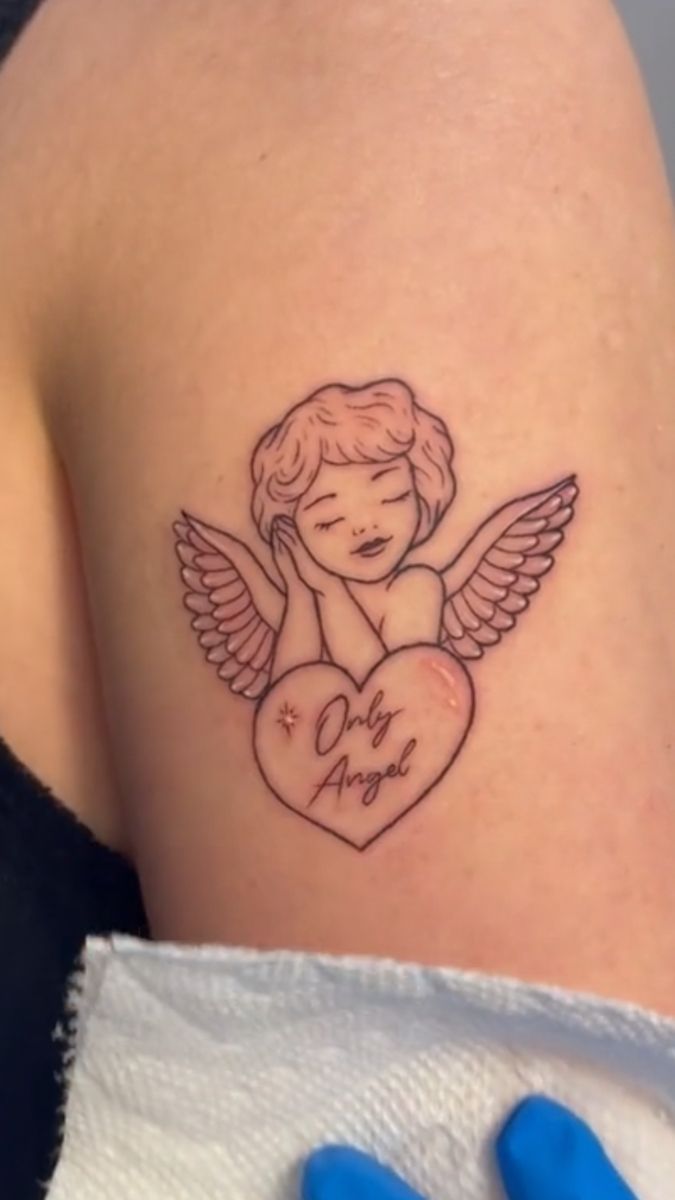 a small tattoo on the back of a woman's arm with an angel holding a heart