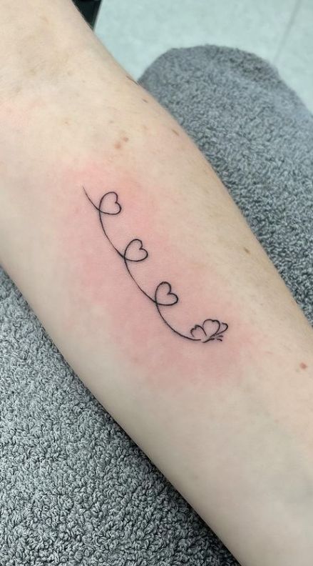 a woman's arm with the word love written in cursive hearts on it