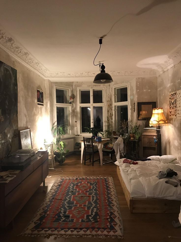 a bed room with a neatly made bed and a rug on the floor in front of two windows