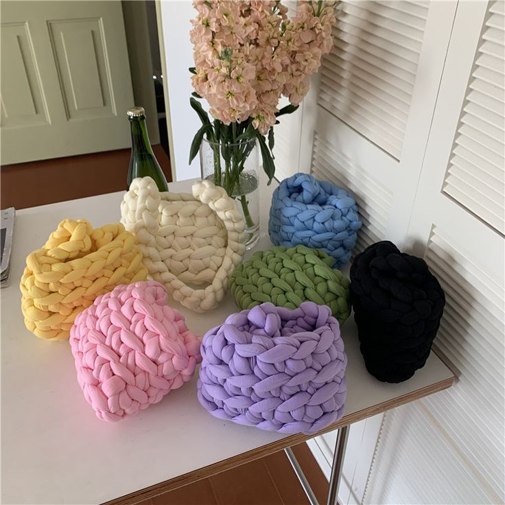 four different colored towels sitting on top of a table next to a vase with flowers