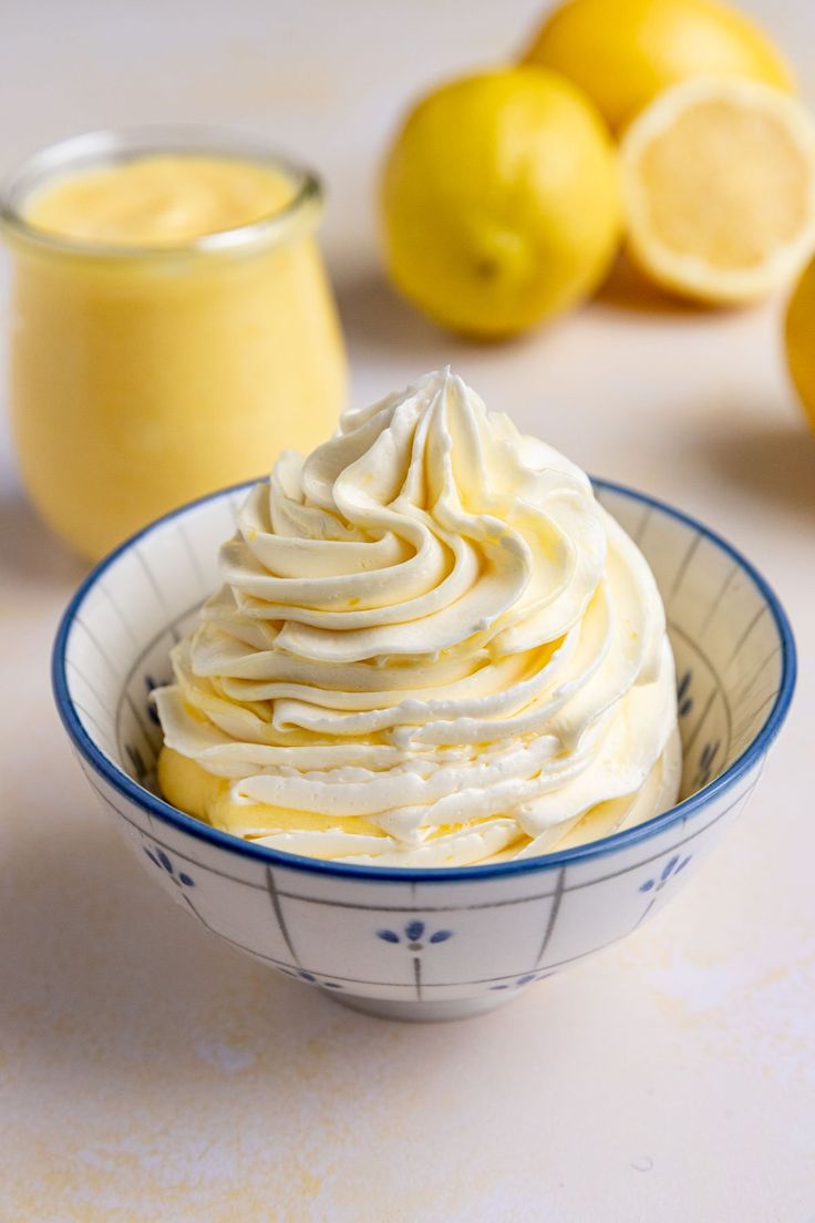 a bowl filled with whipped cream next to lemons