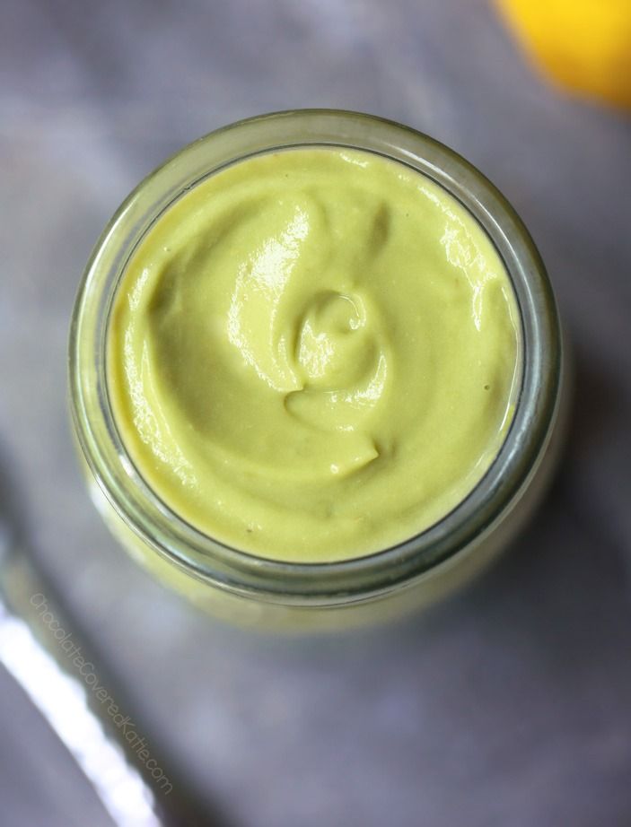 a glass jar filled with green liquid next to two lemons and a spoon on a table