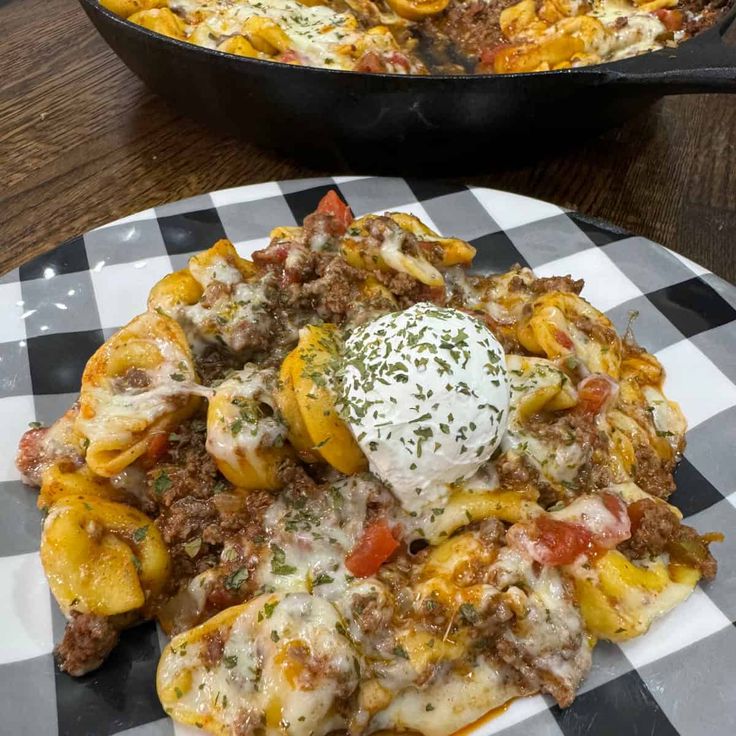 a close up of a plate of food on a table with a skillet in the background