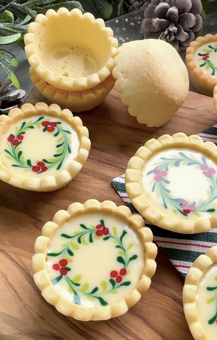 small pies with painted designs on them sitting on a wooden table next to pine cones