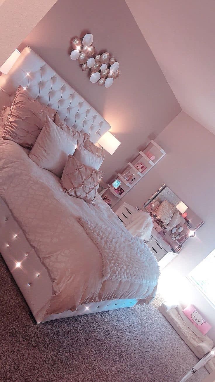 a bedroom with pink walls and white headboard, lights on the nightstands and bed