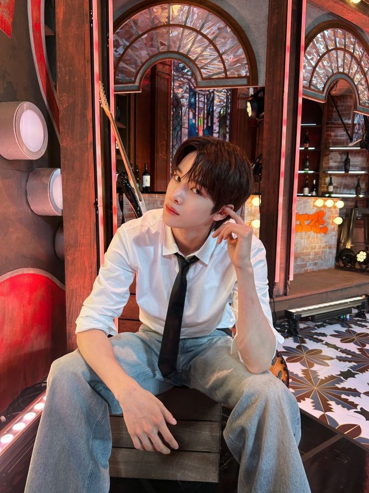 a young man sitting on top of a wooden bench wearing a tie and white shirt