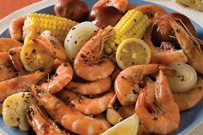 a blue plate topped with shrimp, corn and potatoes