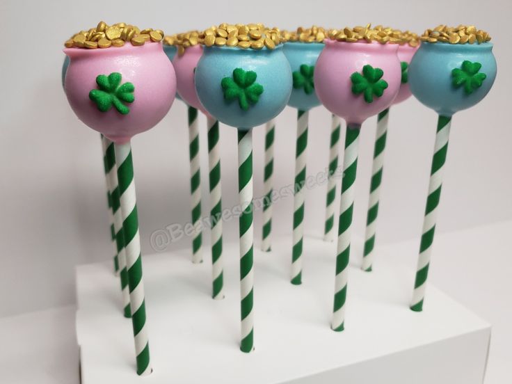 four candy lollipops decorated with shamrock leaves and gold flakes on them