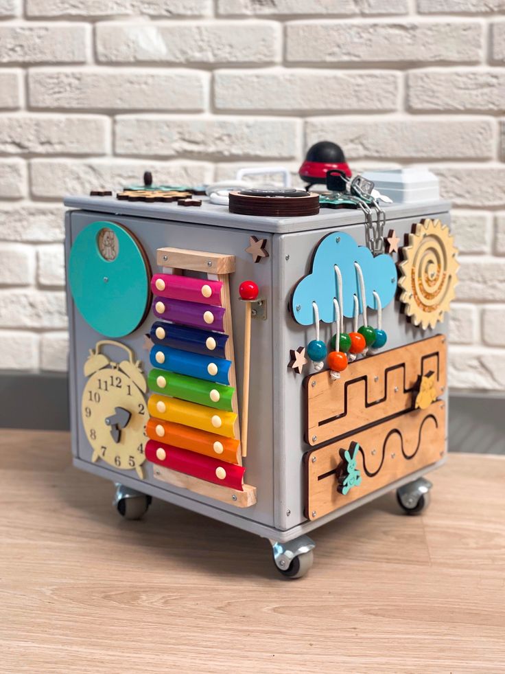 a toy box with an assortment of musical instruments in it on a table next to a brick wall