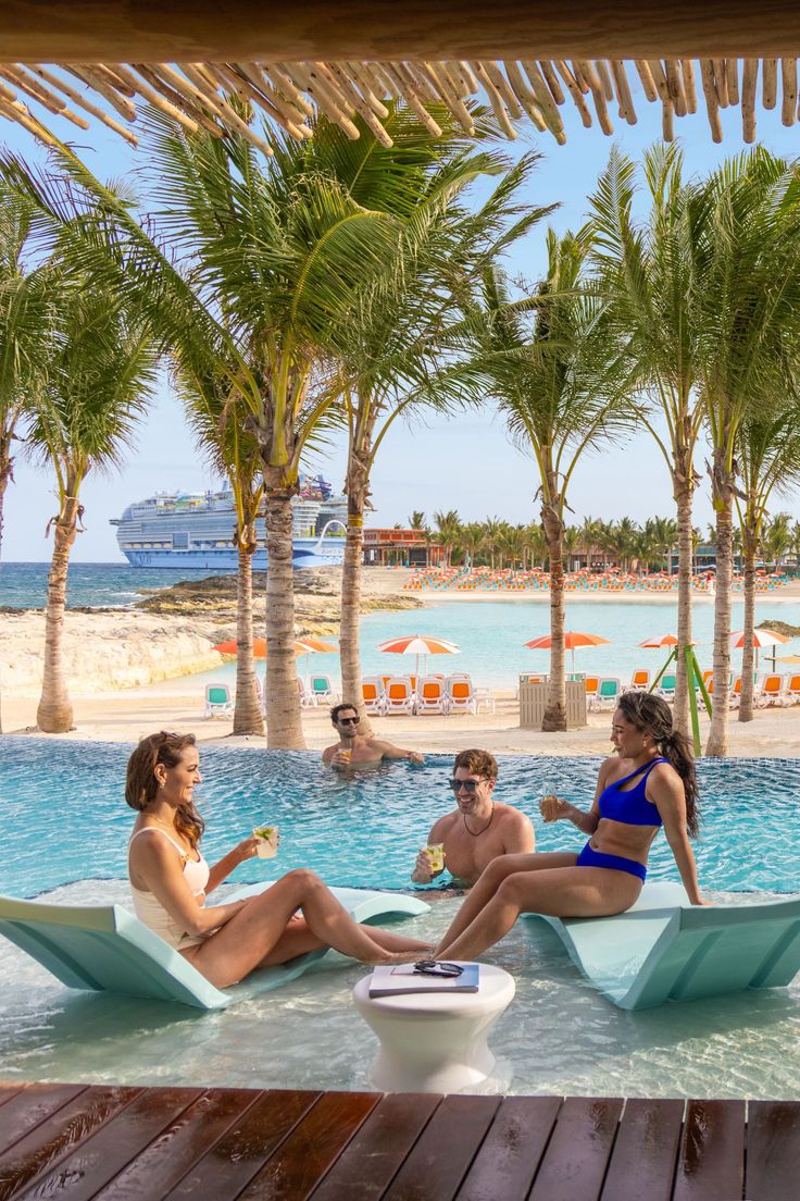 three people sitting on chaise lounges at the edge of a swimming pool with palm trees in the background