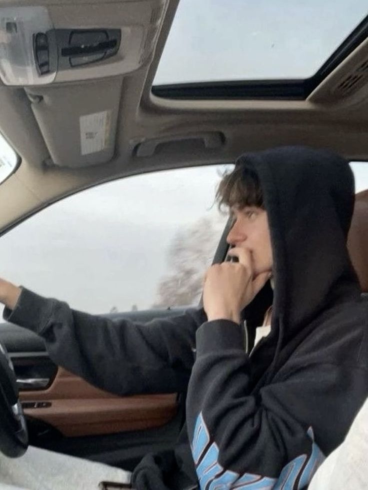 a man sitting in the driver's seat of a car talking on his cell phone