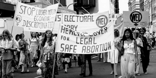 a group of people marching down the street with signs on them and banners in front of them