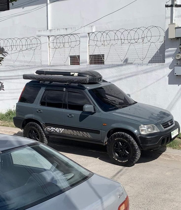 an suv parked in front of a white wall with razor razors on the top