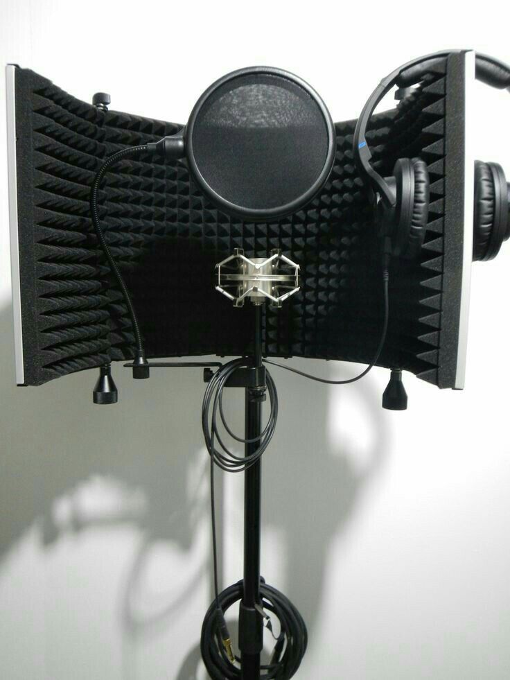 a microphone with headphones attached to it on a tripod in front of a white wall