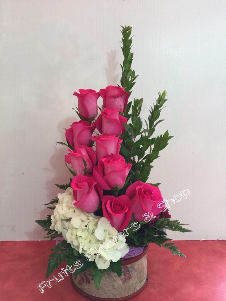 a bouquet of pink roses and white hydrangeas in a tin vase on a table