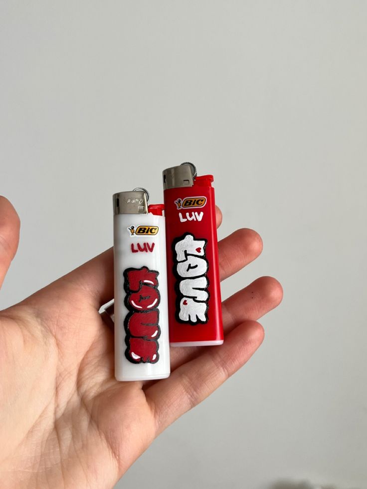 a person holding two lighters in their hand, one is red and the other is white