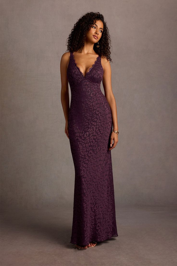 a woman in a long purple dress posing for the camera with her hand on her hip