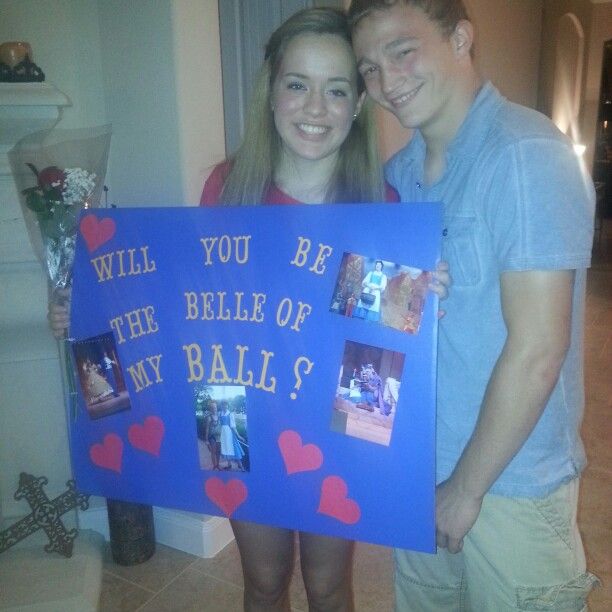 two people standing next to each other holding up a blue sign with hearts on it that says will you be the bell of my ball?