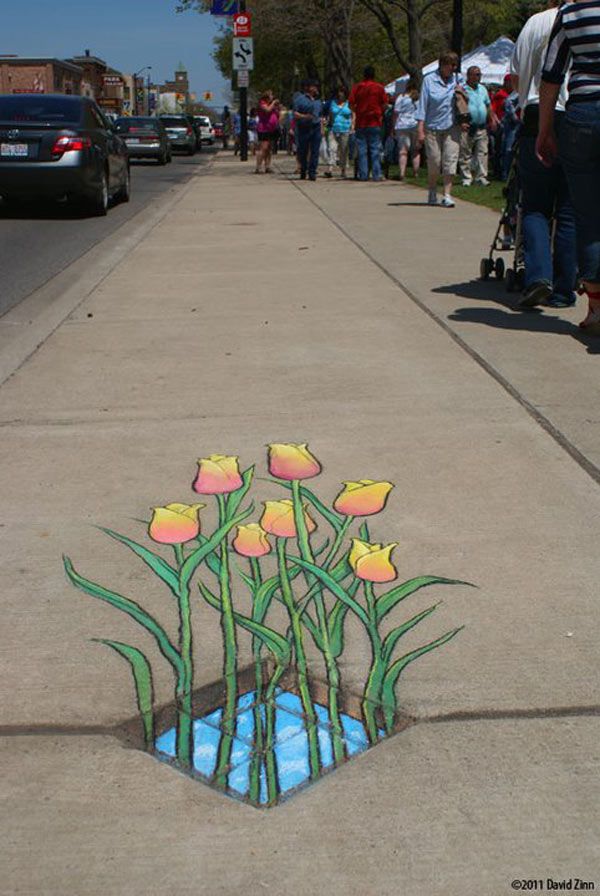 the sidewalk has been painted with flowers and water in it, while people are walking by