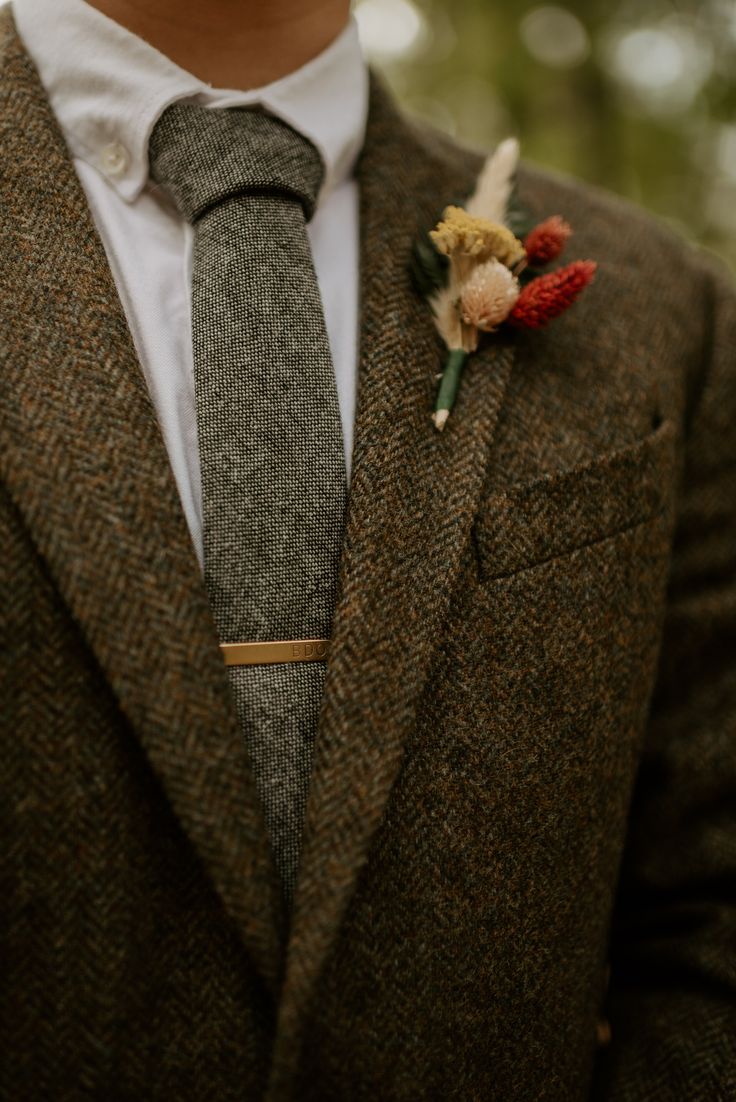 a man wearing a suit and tie with a boutonniere on his lapel