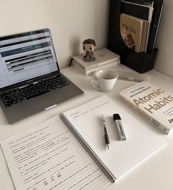 an open laptop computer sitting on top of a desk next to a cup of coffee