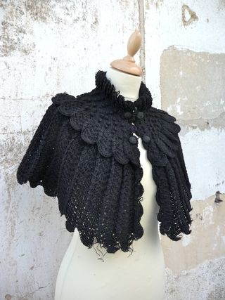 a white mannequin wearing a black crochet shawl