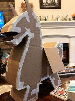 an animal made out of cardboard sitting on top of a table next to a fireplace