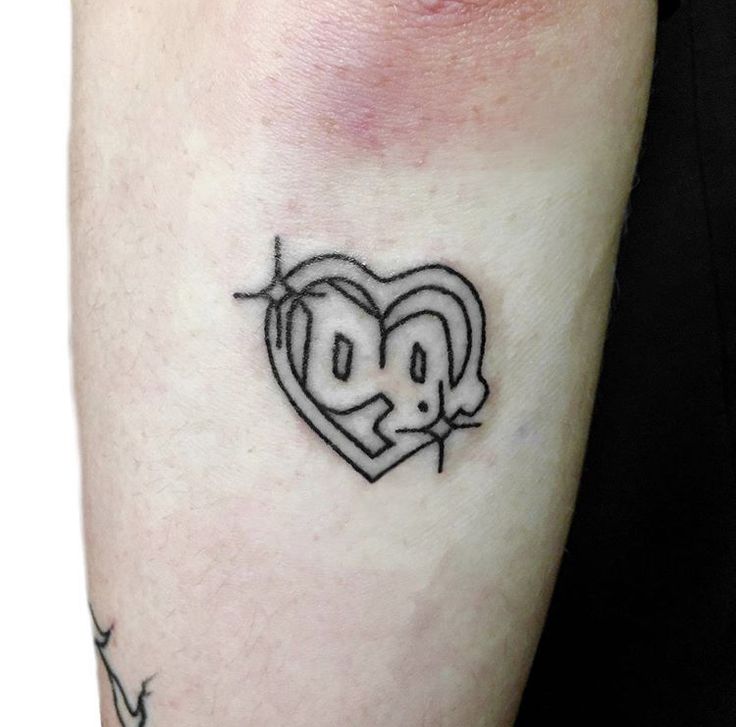 a small heart tattoo on the arm with an emo face and arrow around it