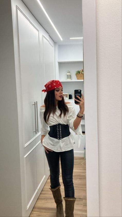 a woman taking a selfie in a hallway wearing pirate costume and holding a cell phone