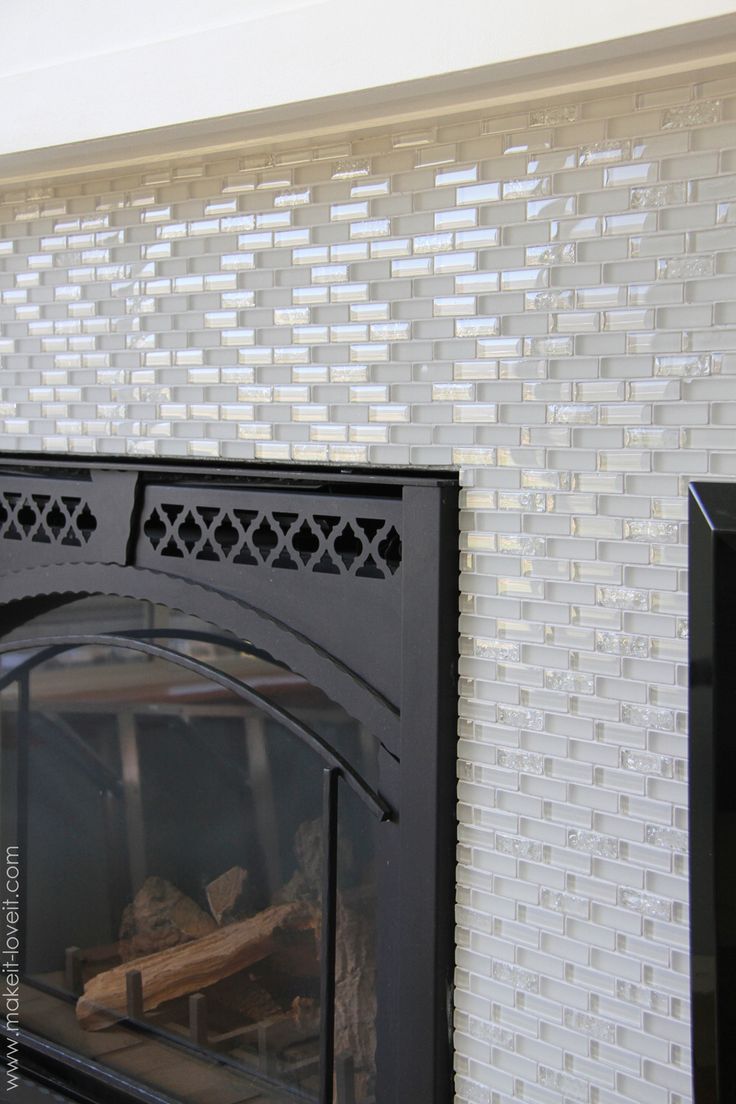 a black fireplace with white tiles on the wall