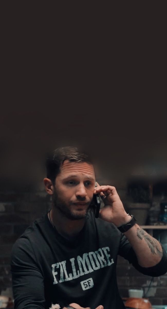 a man sitting at a table talking on a cell phone