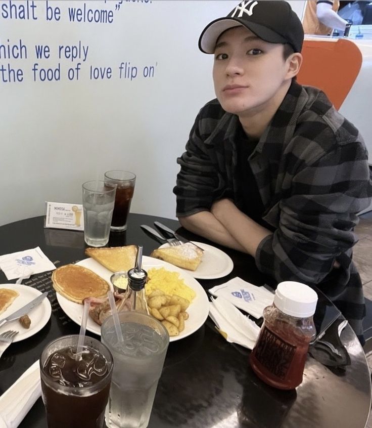 a man sitting at a table with plates of food and drinks in front of him