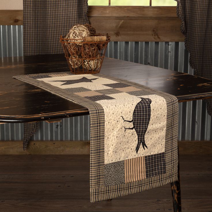 a table with a black and white quilt on top of it next to a window