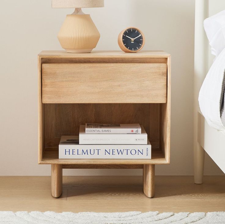 a nightstand with books and a clock on it