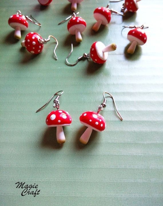 red and white mushrooms are hanging from silver earwires on a green table top