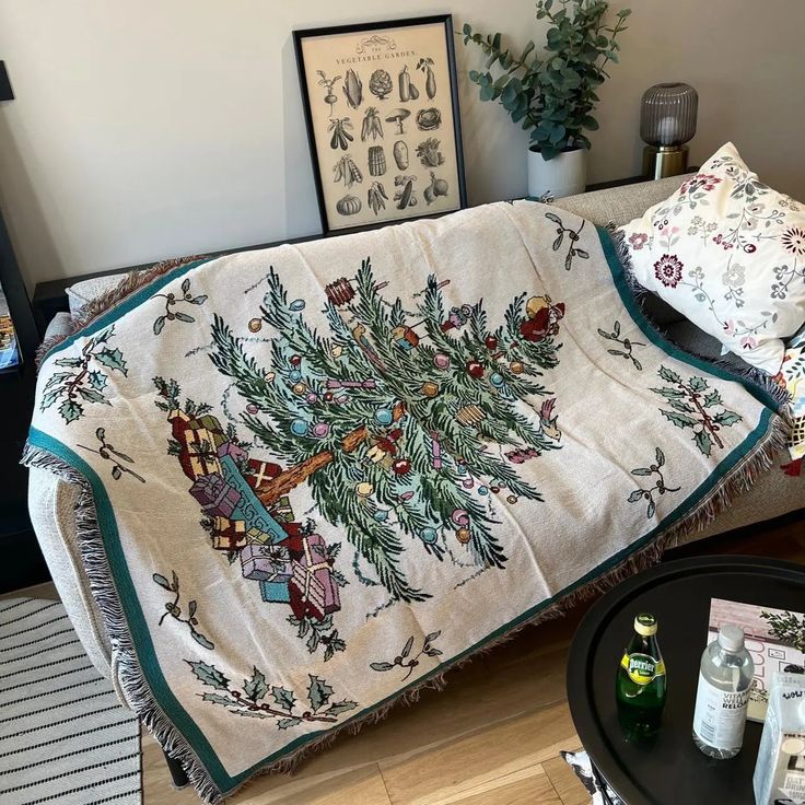 a living room with a couch covered in a christmas tree blanket and pillows on top of it