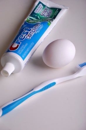 two toothbrushes and an egg on a table